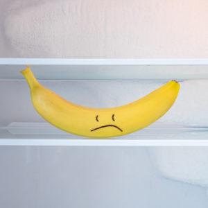 Banana with a frowny face drawn on in a fridge