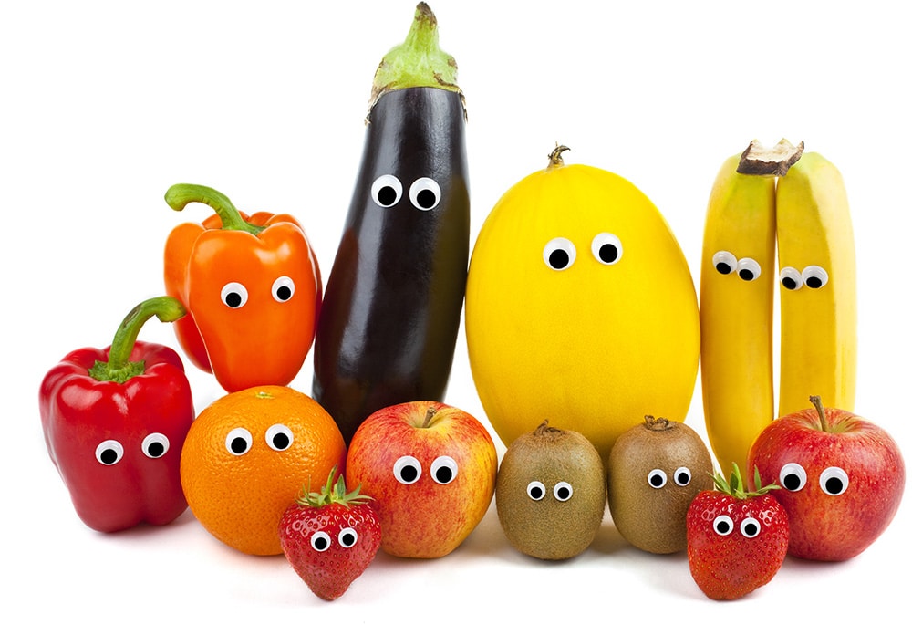 Various fruits and vegetables with googley eyes on a white background