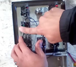 A hand pressing the contact block into place on the backside of a new button in the control panel of a Juiced Rite machine