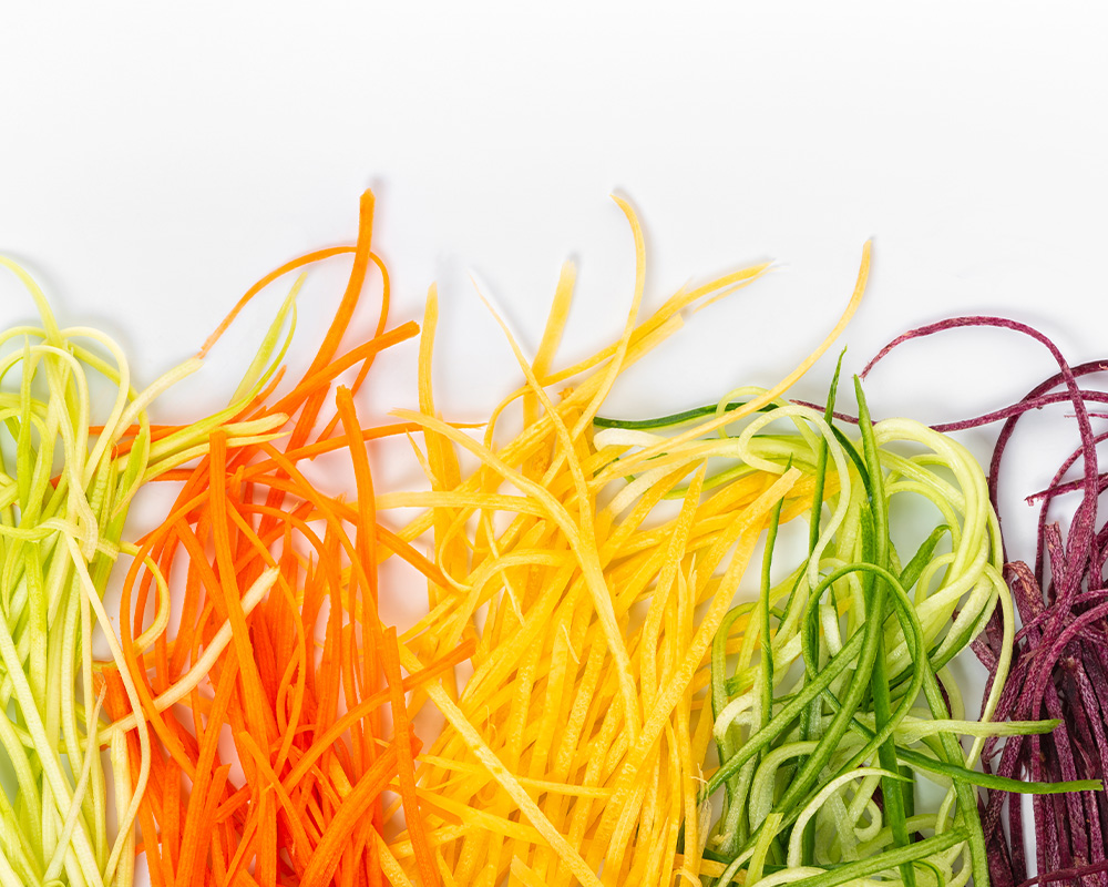 Noodle Cut Vegetables laid out in colors on a white background
