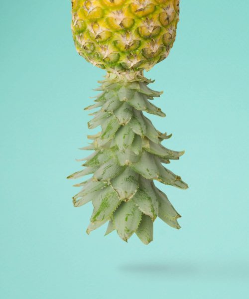 top of a pineapple coming out of the top of the picture on a blue background