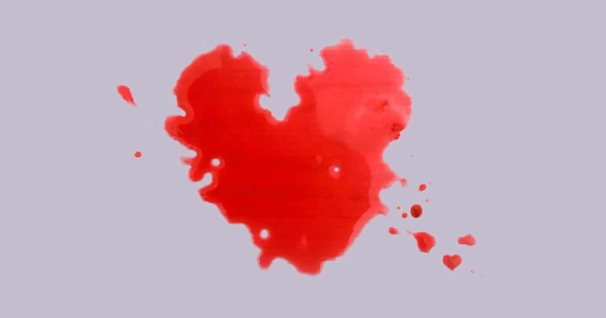 Photo of a red juice spilled in the shape of a heart to show that making cold press juice is messy.